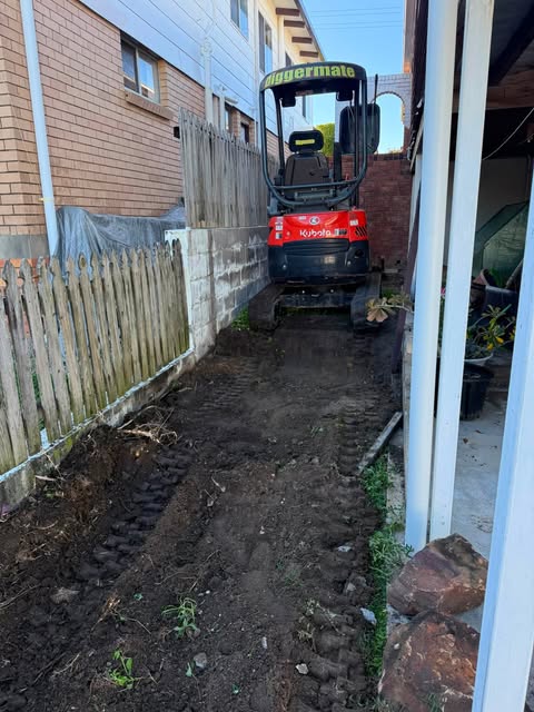 A machine working in a narrow gap between a house and a fence